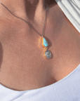 Close-up of a turquoise coin necklace featuring a diamond-shaped turquoise stone and an ancient Roman coin.