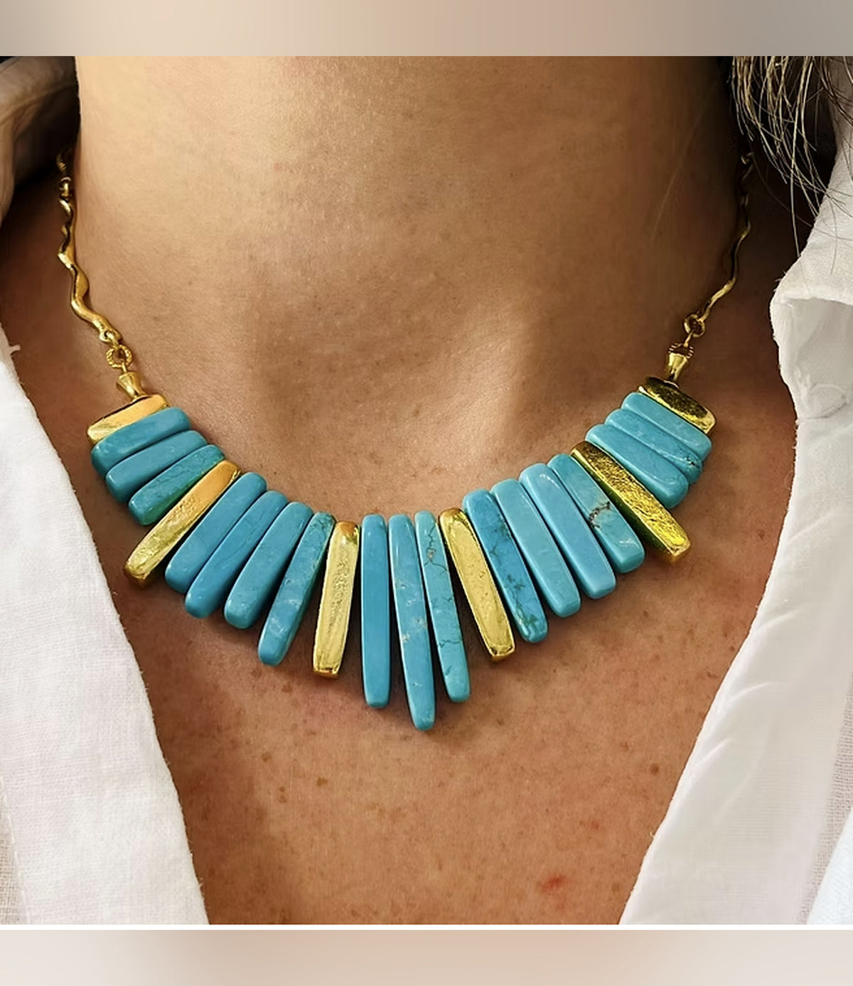 Aegean Turquoise Necklace with graduated turquoise-blue bars and gold-tone accents worn with a white shirt