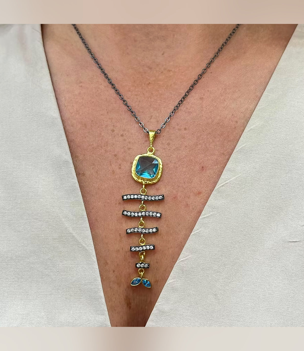 Azure Cascade Aquamarine Necklace with cascading embellished bars and blue drops worn against a white neckline