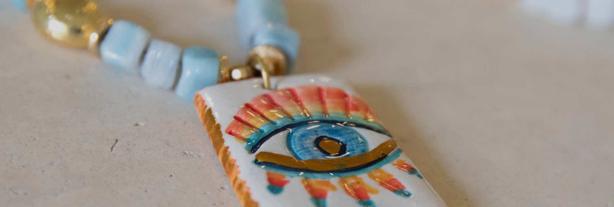 Colorful eye-shaped pendant on a chain with a beige background
