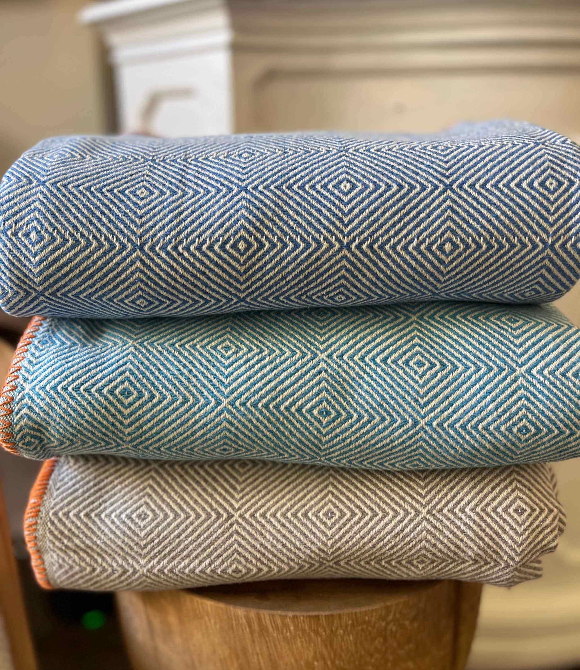 Stack of three patterned fabric rolls on a wooden surface