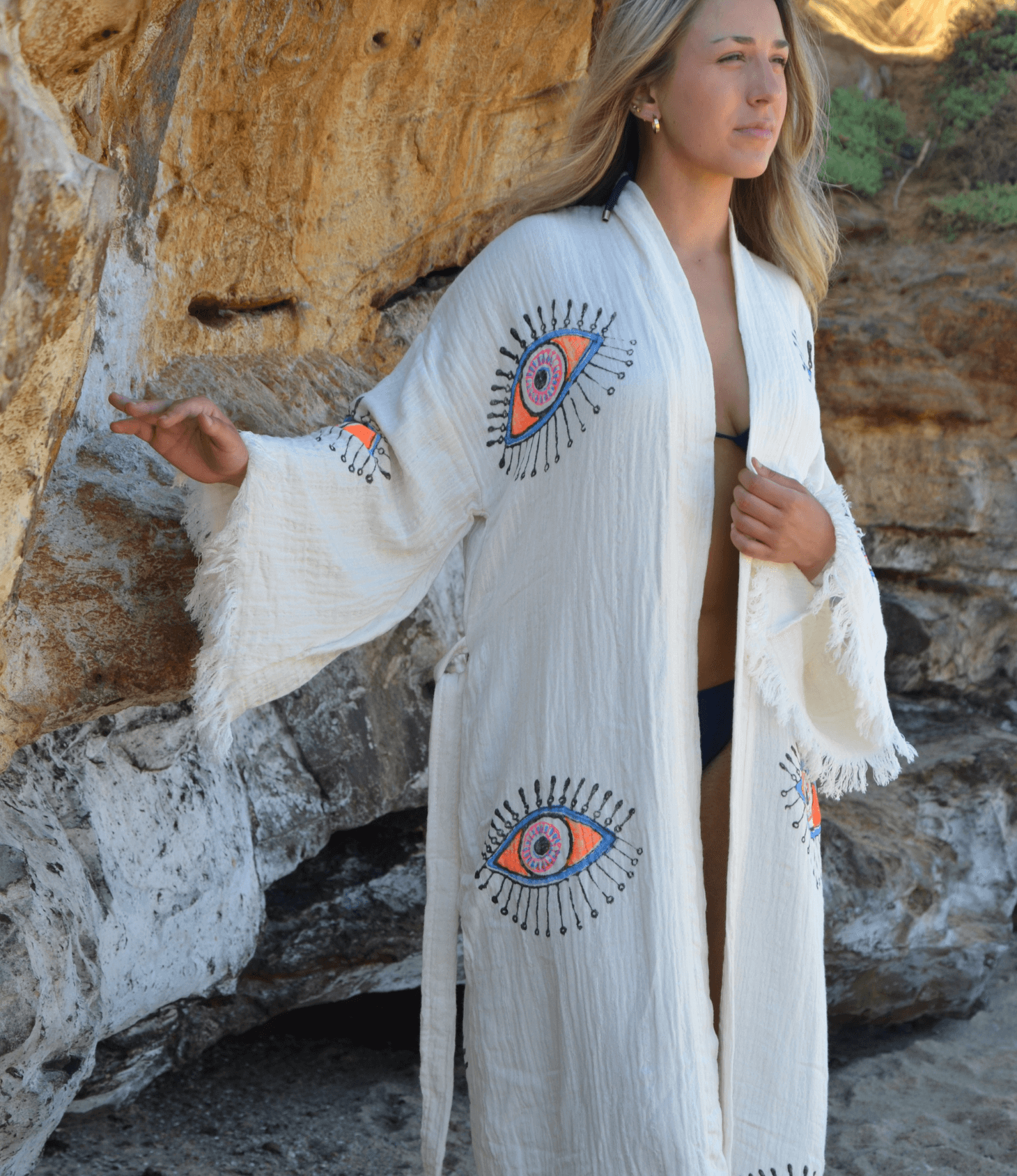 Model wearing a handcrafted Evil Eye Robe made from soft Buldan muslin cotton by the beach.