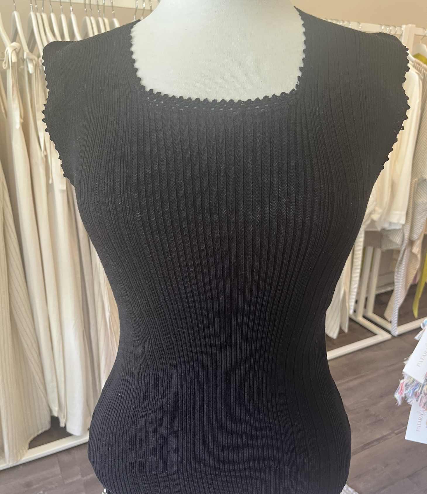 Black ribbed tank top on a mannequin with a blurred indoor background
