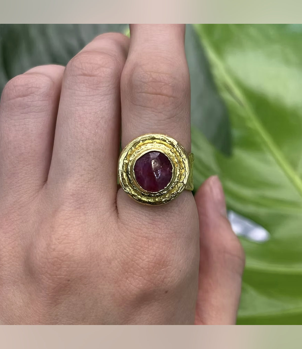 Rhea Red Statement Ring with a deep-red oval centrepiece and layered gold-tone setting, worn on a hand