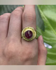 Rhea Red Statement Ring with a deep-red oval centrepiece and layered gold-tone setting, worn on a hand