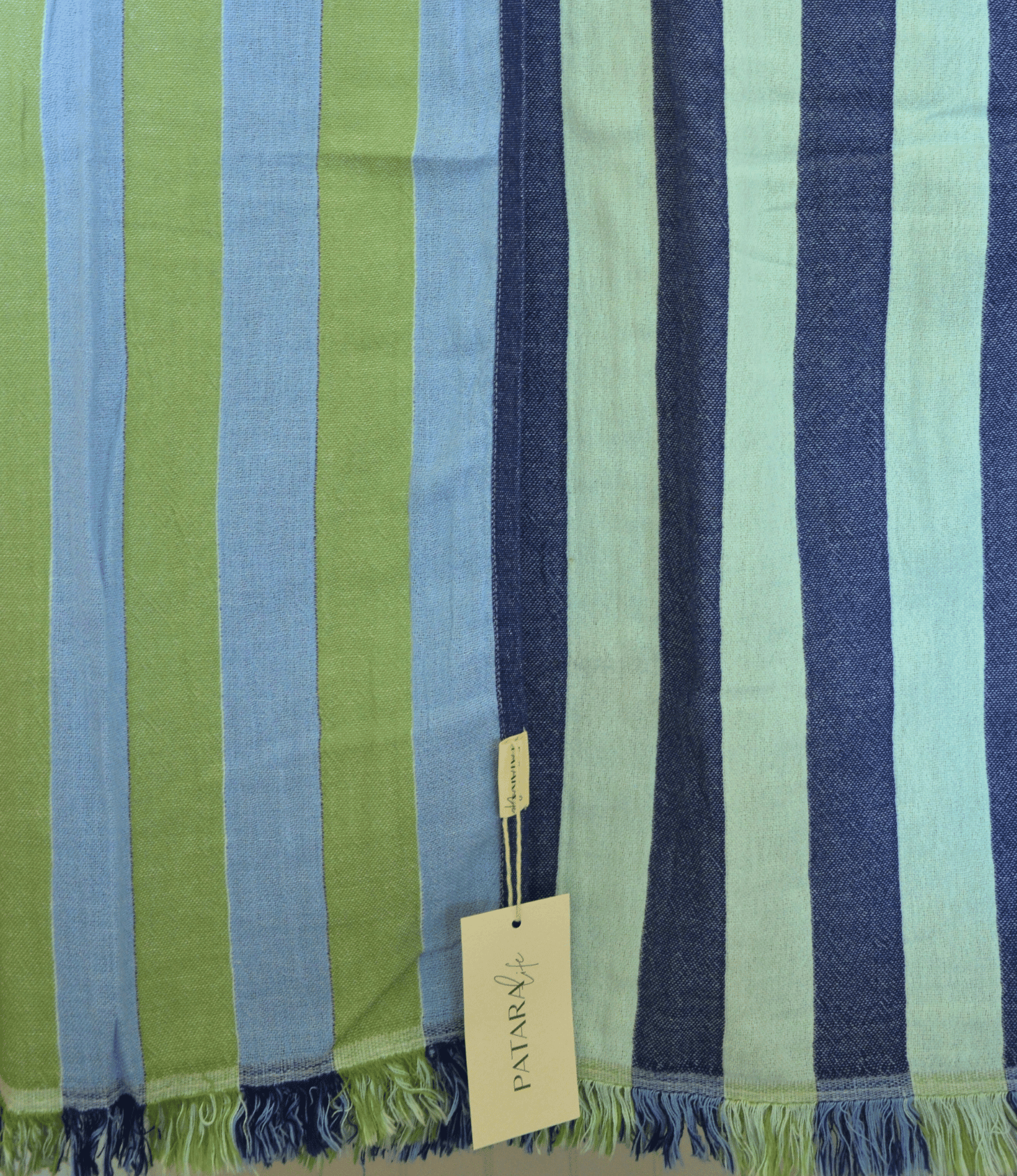 Striped fabric with green, blue, and navy colors and a visible brand tag.