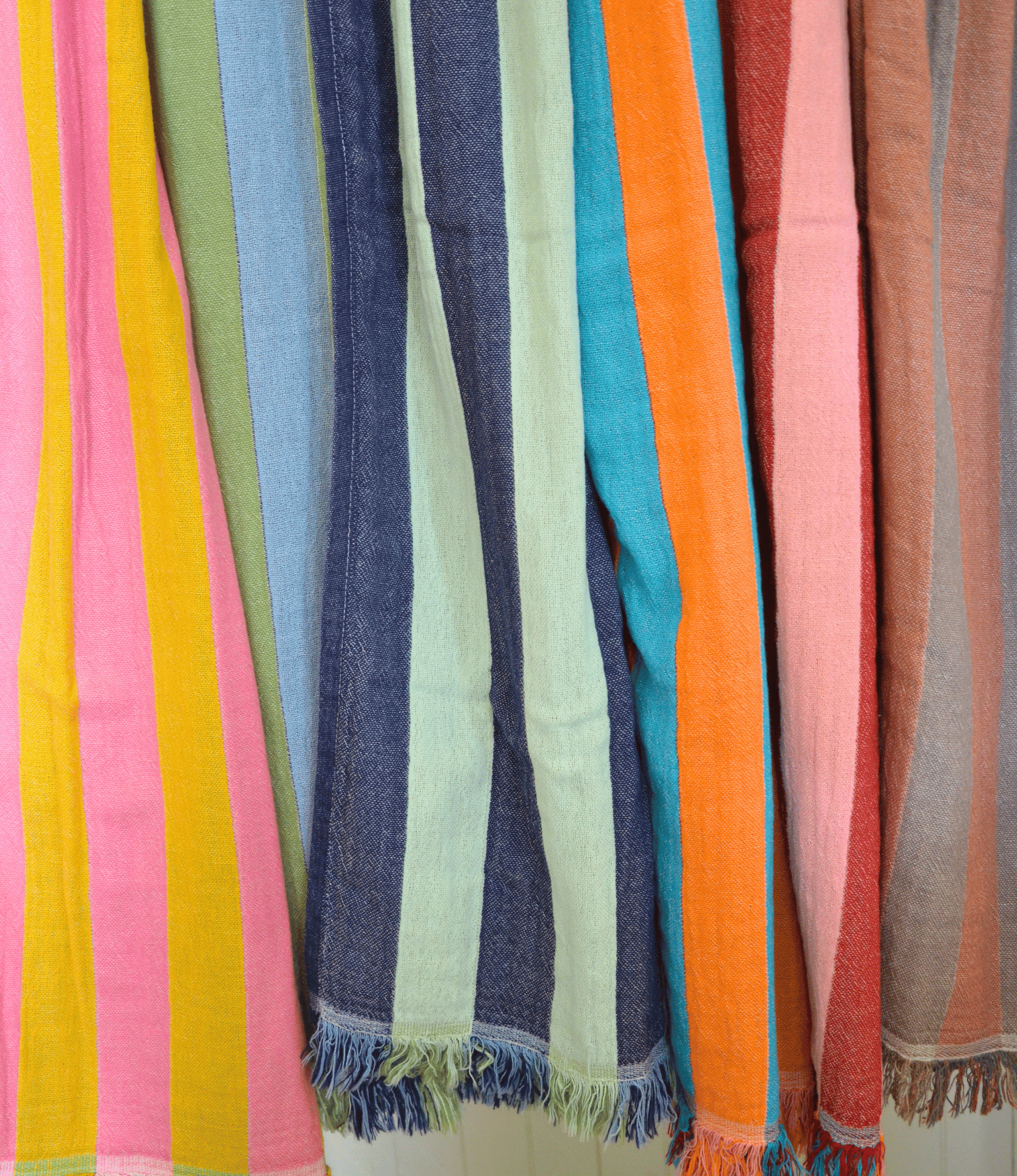 Colorful striped fabric with fringes in various colors on a white background