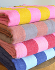 Stack of colorful folded fabrics with circular patterns on a wooden surface.