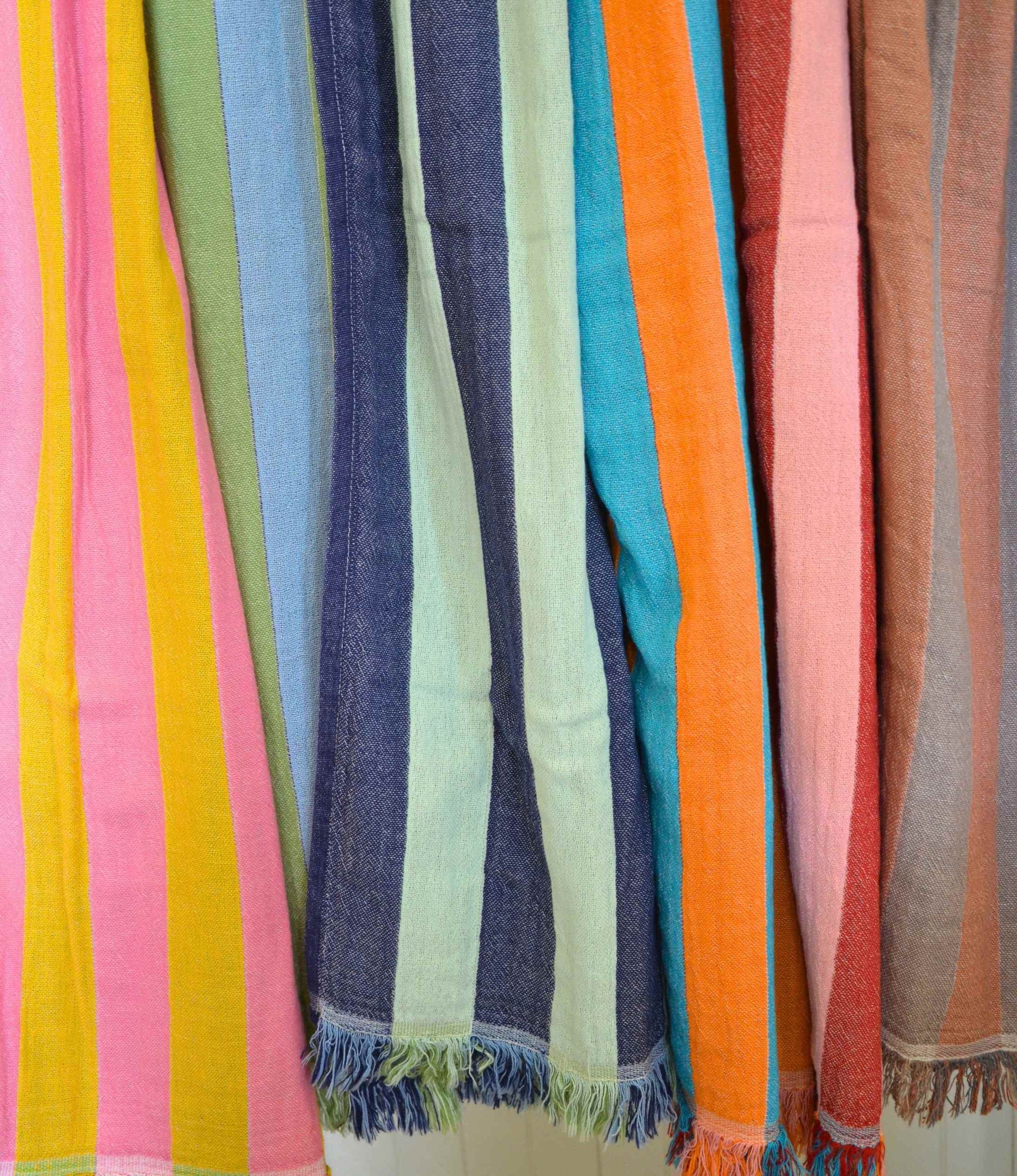 Colorful striped cotton towels with fringes hanging side by side