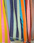 Colorful striped cotton towels with fringes hanging side by side