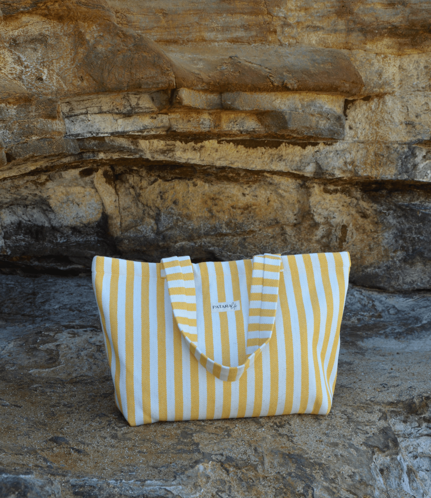 yellow beach tote bag on a beach rock cliff