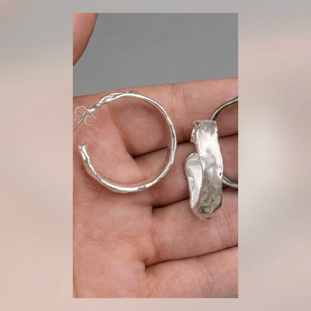 Enhanced detail shot of the Sculpted Silver Hoops pair in hand