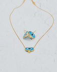 Gold necklace with blue evil eye pendants on a light gray background