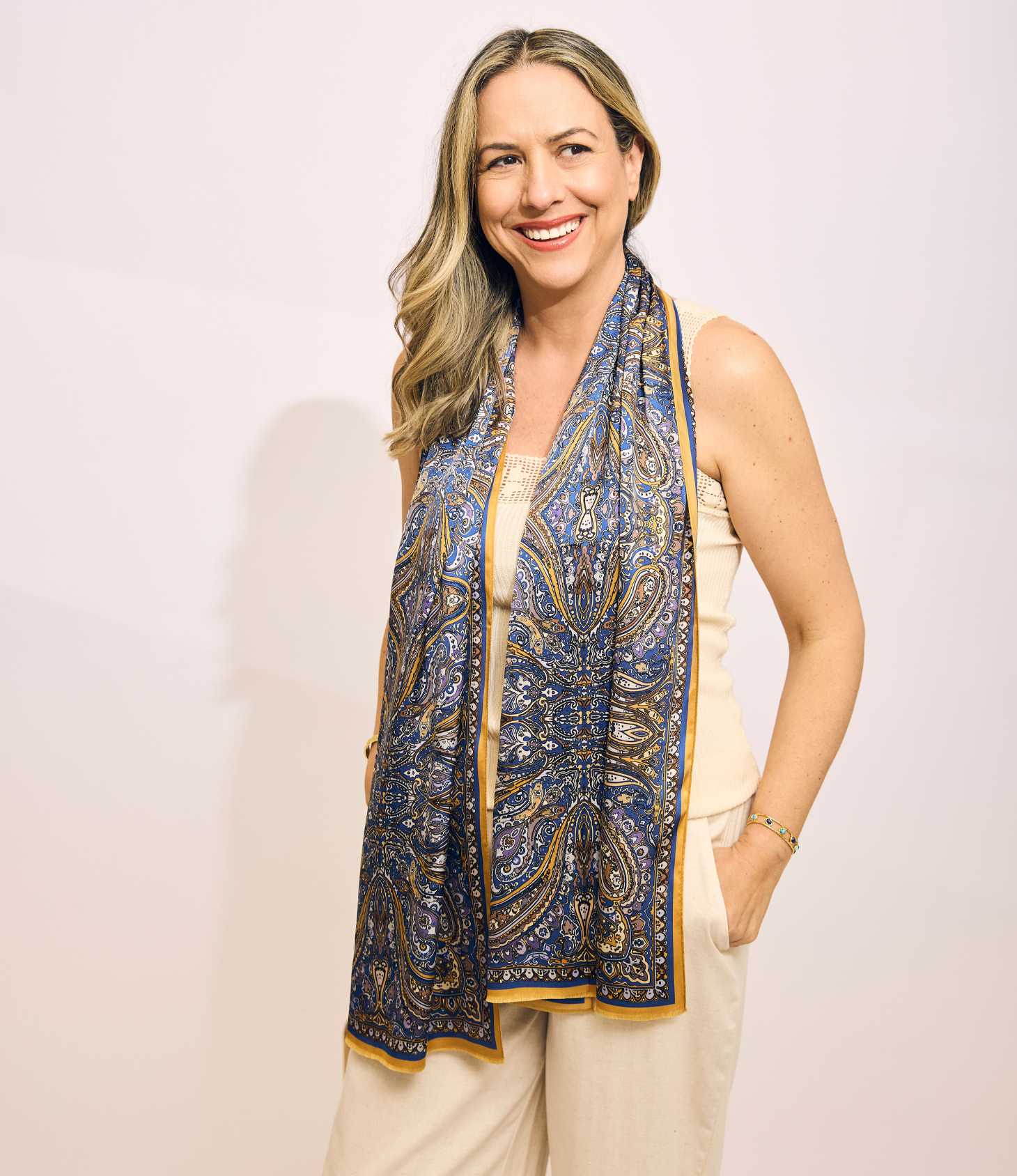 Woman wearing a blue paisley scarf on a plain background