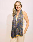 Woman wearing a blue paisley scarf on a plain background