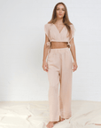 A female model wearing a pink 'Alinda' two-piece outfit, consisting of a crop top and wide-leg pants.