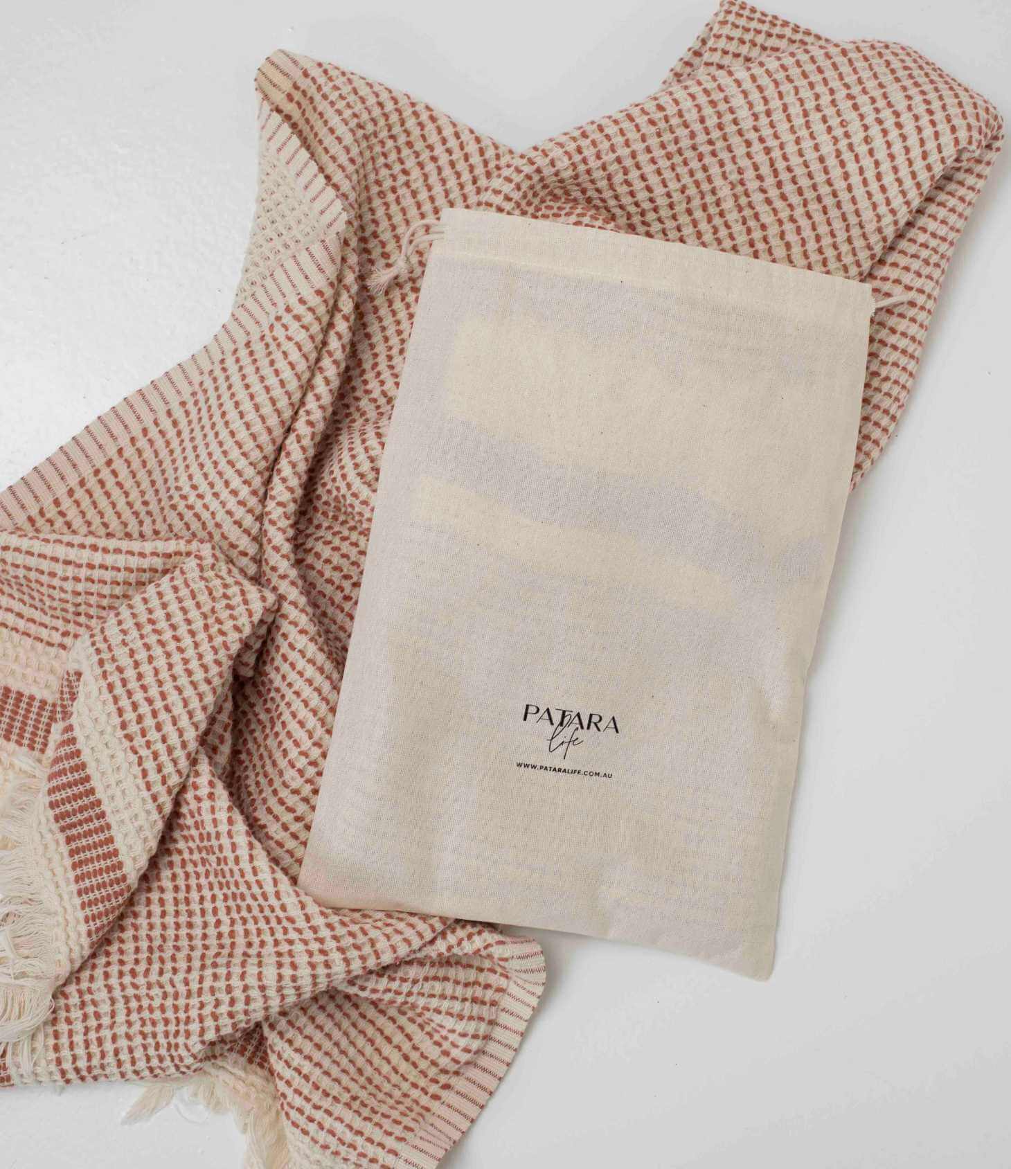 A dotted &quot;Kalkan&quot; beach towel layed out with drawstring bag on top