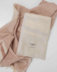 A dotted "Kalkan" beach towel layed out with drawstring bag on top