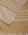 Close up of a mustard yellow linen & cotton premium throw layed flat