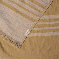 Close up of a mustard yellow linen & cotton premium throw layed flat