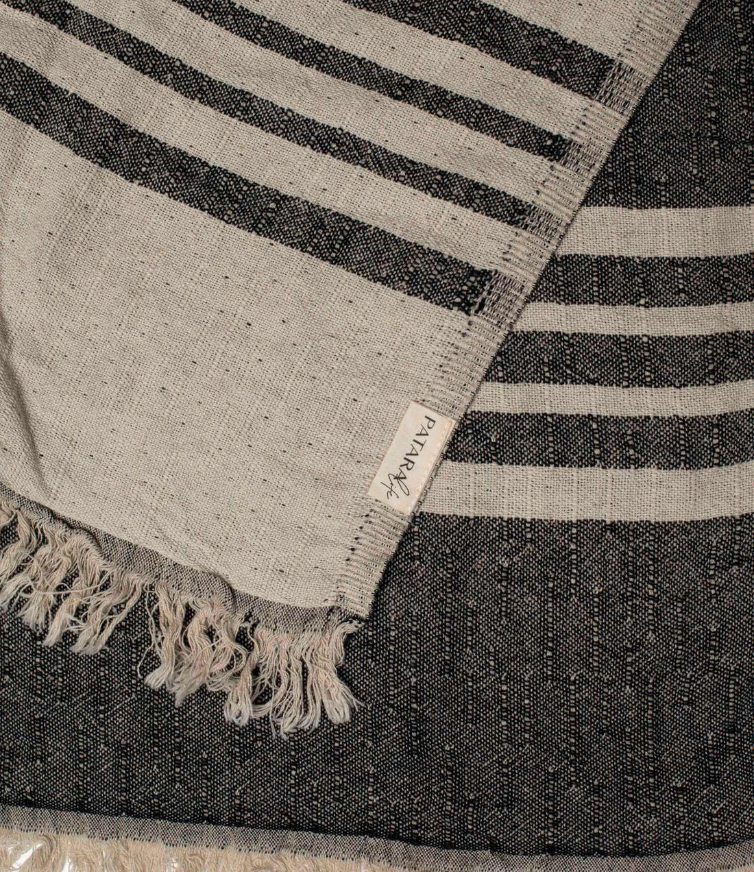 Close up of a black and beige linen & cotton premium throw layed flat