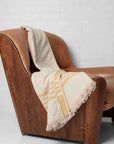 A yellow and beige throw draped over leather armchair