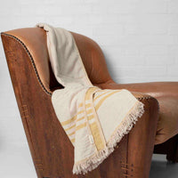 A yellow and beige throw draped over leather armchair
