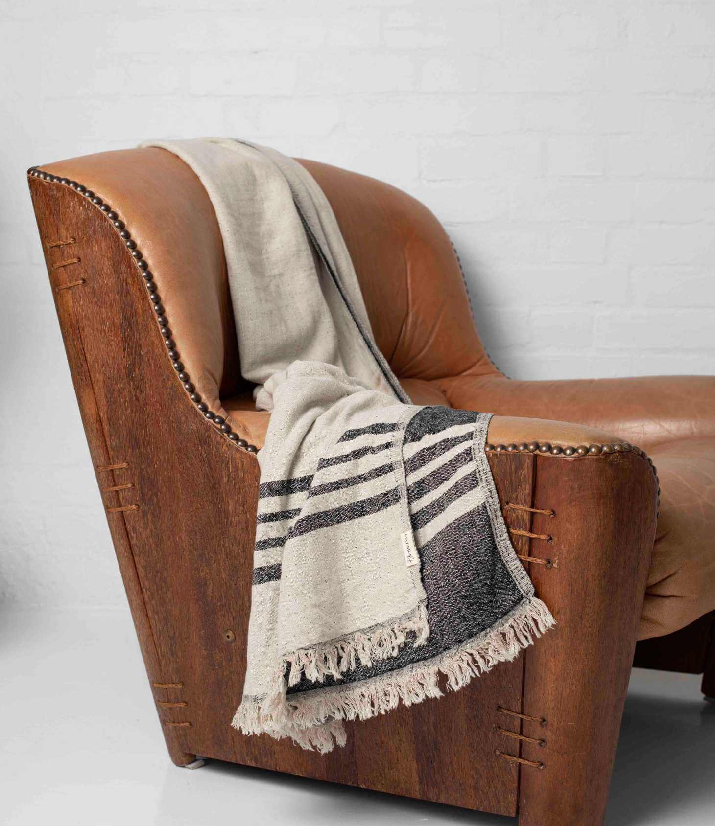 A black and beige throw draped over leather armchair