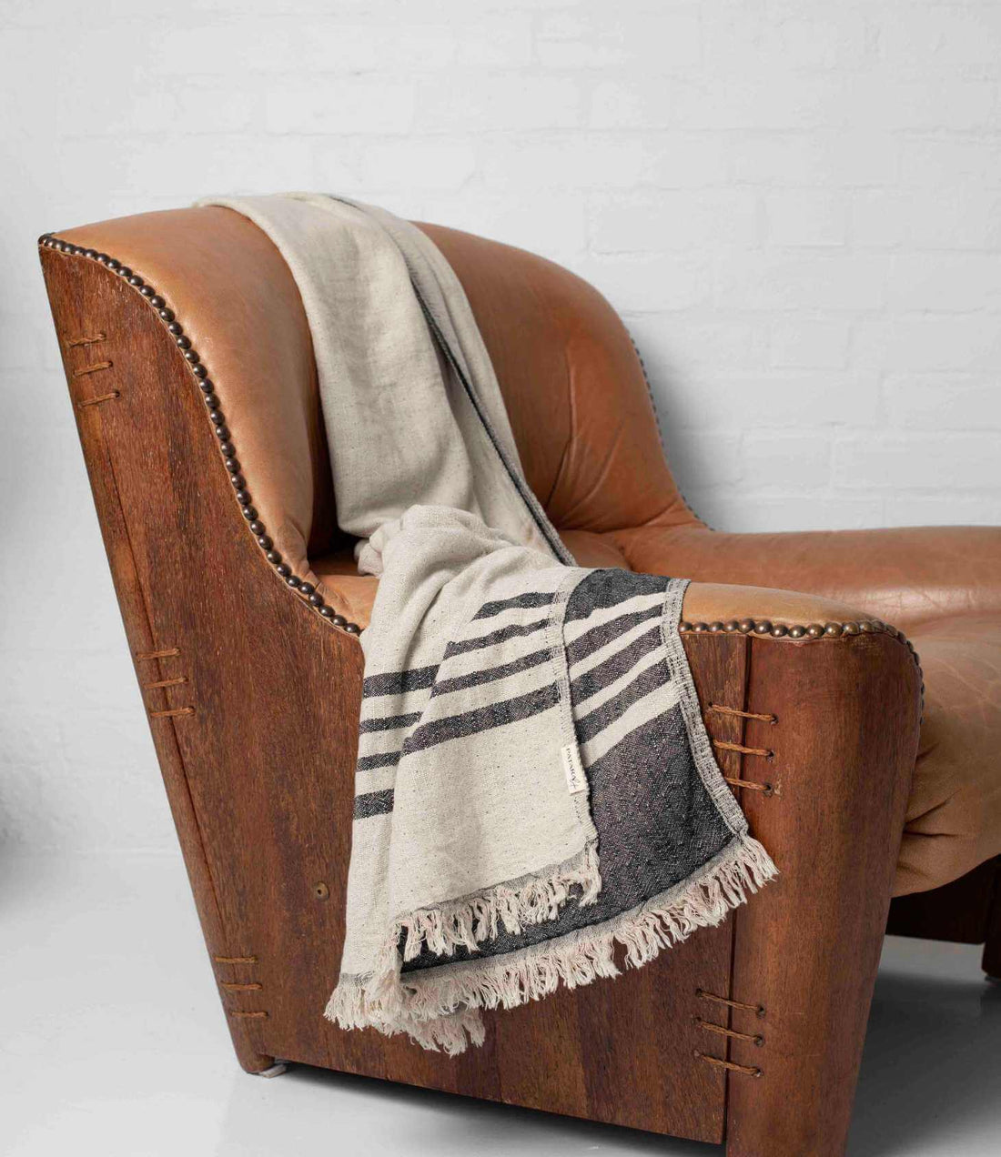 A black and beige throw draped over leather armchair