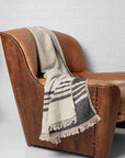 A black and beige throw draped over leather armchair